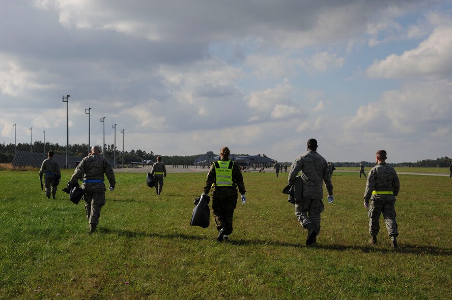 U.S. Air Force Airmen assigned to the 74th Expeditionary Fighter Squadron and members of the Estonian air force walk back after conducting a foreign object debris walk on the flight line at Amari Air Base, Estonia, Sept. 25, 2015. FOD walks are a preventative measure that helps eliminate debris that could cause damage to aircraft. (U.S. Air Force photo by Andrea Jenkins/Released)