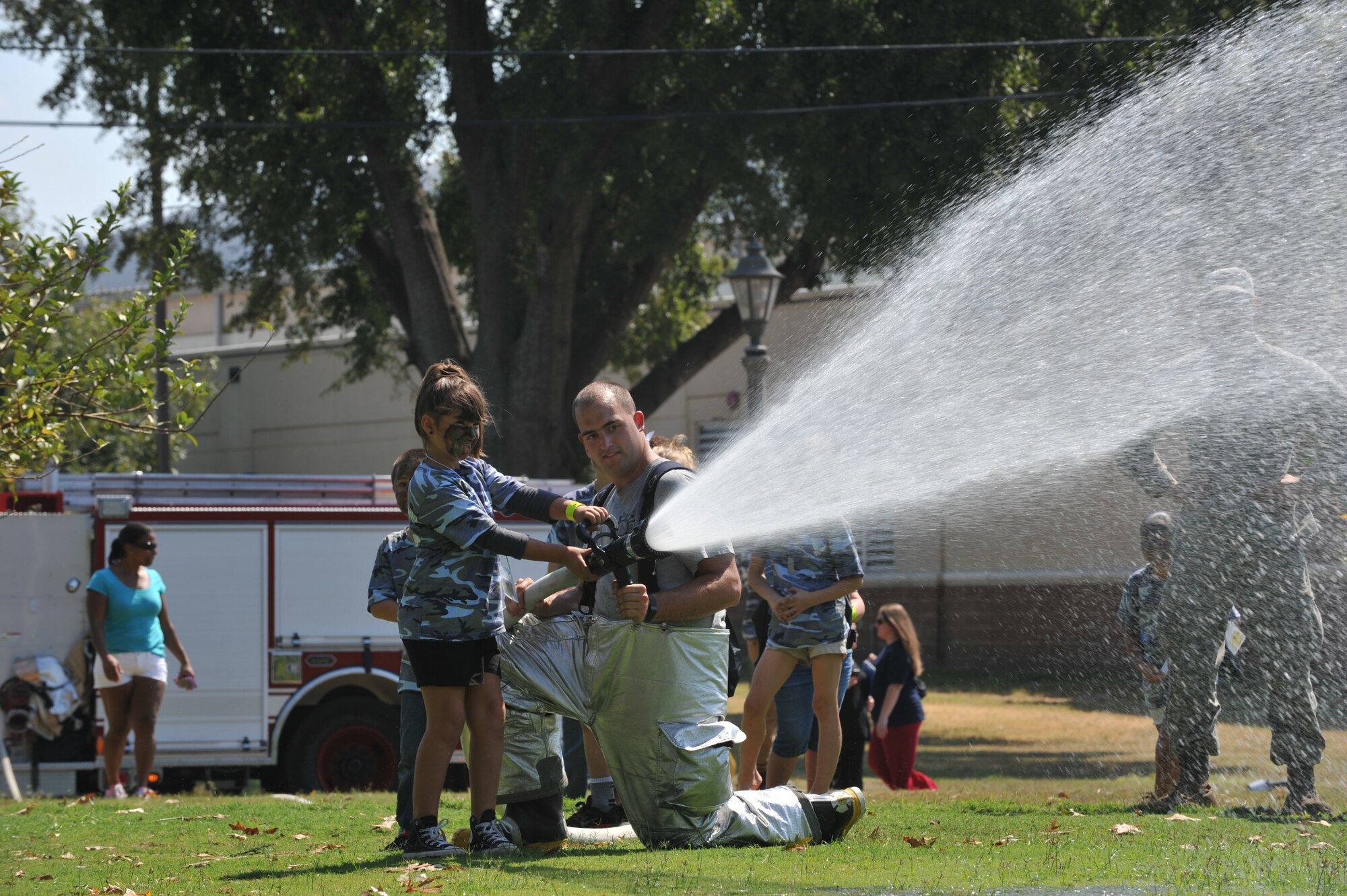 Barksdale firefighters show participants of Operation Hero how to operate a fire hose at Barksdale Air Force Base, La., Sept. 26, 2015. Several base agencies set up displays to teach children about the equipment their parents might use during a deployment. (U.S. Air Force photo/Senior Airman Joseph Raatz)