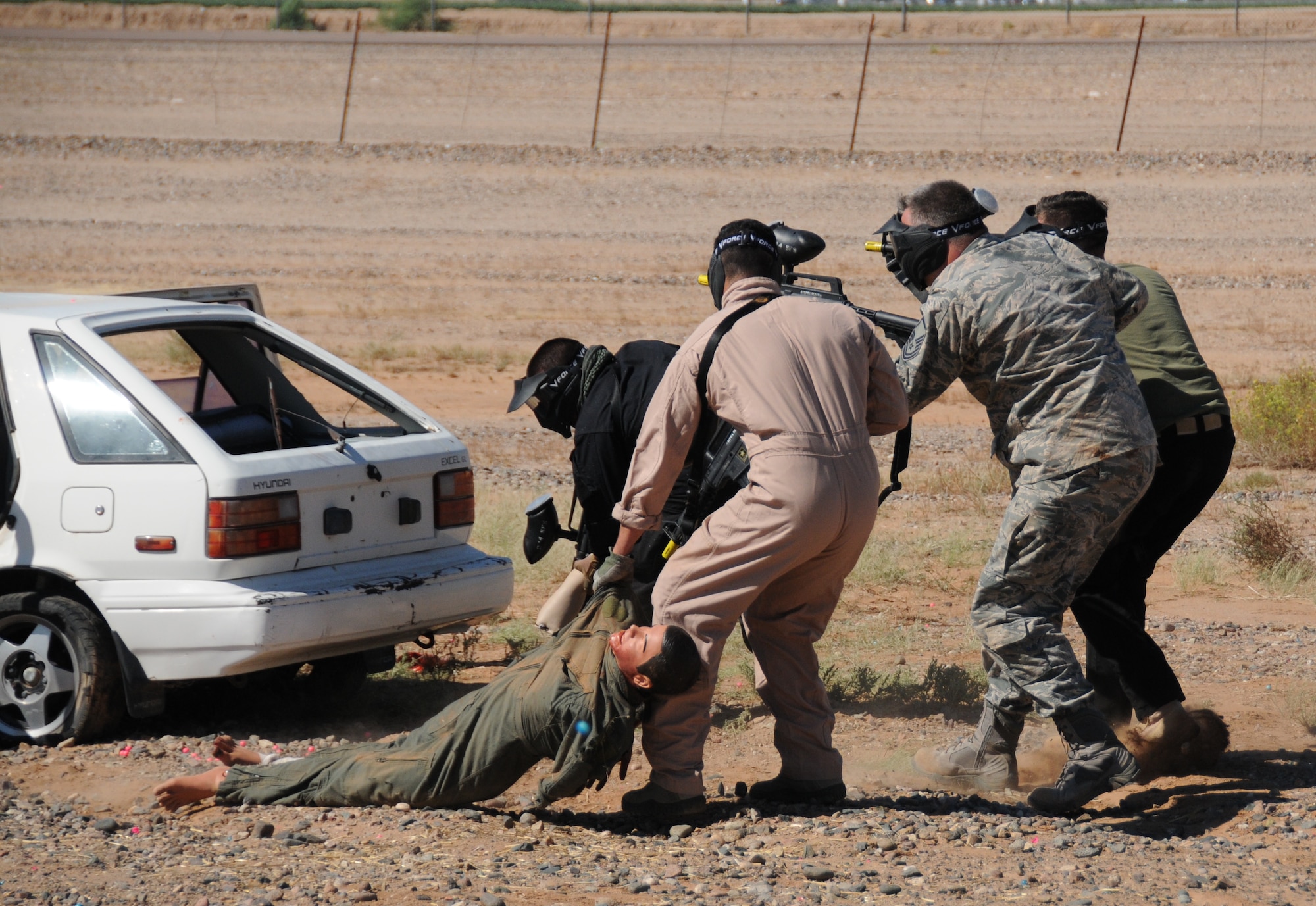Students pull a simulated casualty dummy to safety while under fire during the field exercise portion of the Tactical Combat Casualty Care Course at Luke Air Force Base, Ariz., September 25. TCCC is an international course that provides education for first responders and offers realistic combat experiences in a tactical environment to prepare for upcoming deployments. (U.S. Air Force photo taken by Staff Sgt. Josh Nason)