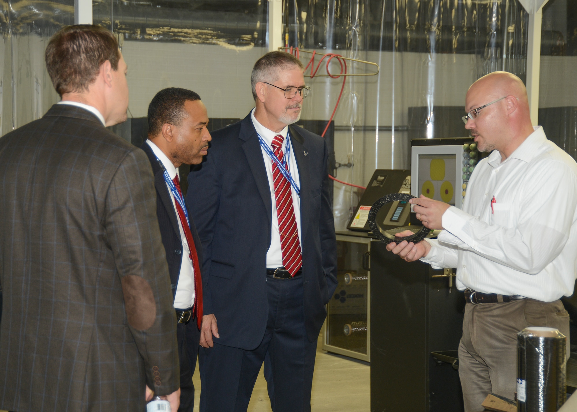 Dr. Dave Walker (center), Deputy Assistant Secretary of the Air Force for Science, Technology, and Engineering, Office of the Assistant Secretary of the Air Force for Acquisition, is shown a composite polar boss by Dr. Greg Yandek (right), Air Force Research Laboratory chemical engineer. The composite polar boss made here at AFRL at Edwards would replace a heavier metal boss on a rocket motor. (U.S. Air Force photo by Kenji Thuloweit)
