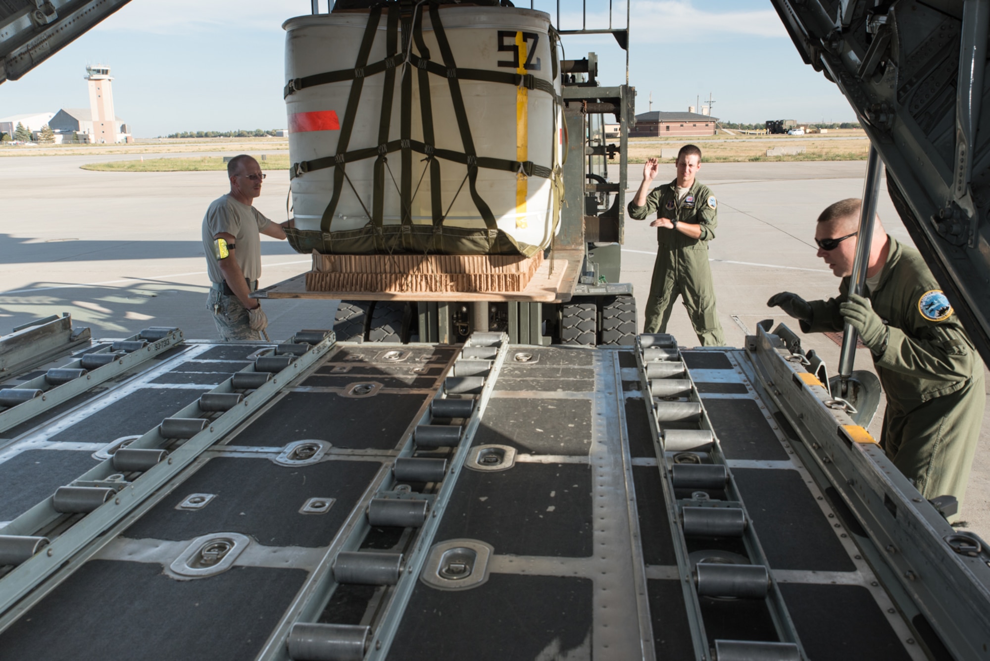 U.S. Air Force loadmasters assigned to the 120th Airlift Wing, Montana Air National Guard work with airmen assigned to the 153rd Logistics Readiness Squadron, Wyoming Air National Guard to load a container delivery system bundle in a C-130H, Sept. 23, 2015, in Cheyenne, Wyoming. The Wyoming Air Guard has been interflying with the Montana Air Guard during their conversion from fighter to cargo aircraft. (U.S. Air National Guard photo by Master Sgt. Charles Delano/Released)