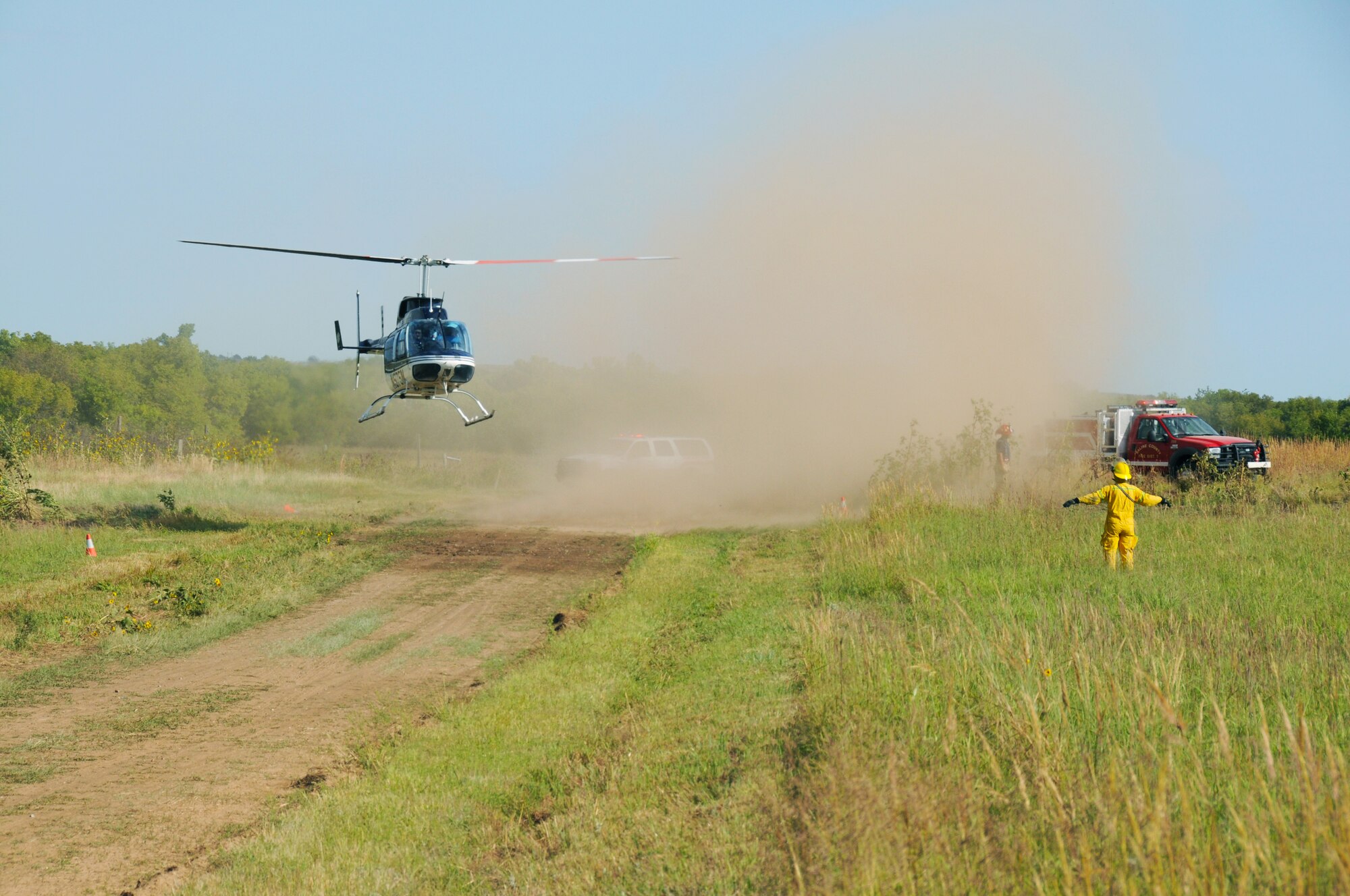A first responder guides a Salina-based Lifeteam helicopter onto a makeshift landing zone close to a C-130 crash site during a major accident response exercise hosted at Smoky Hill Weapons Range. The helicopter landed long enough to load a crash survivor and then transported him to a local medical facility. (Photo by Master Sgt. Matt McCoy, 184th Public Affairs)