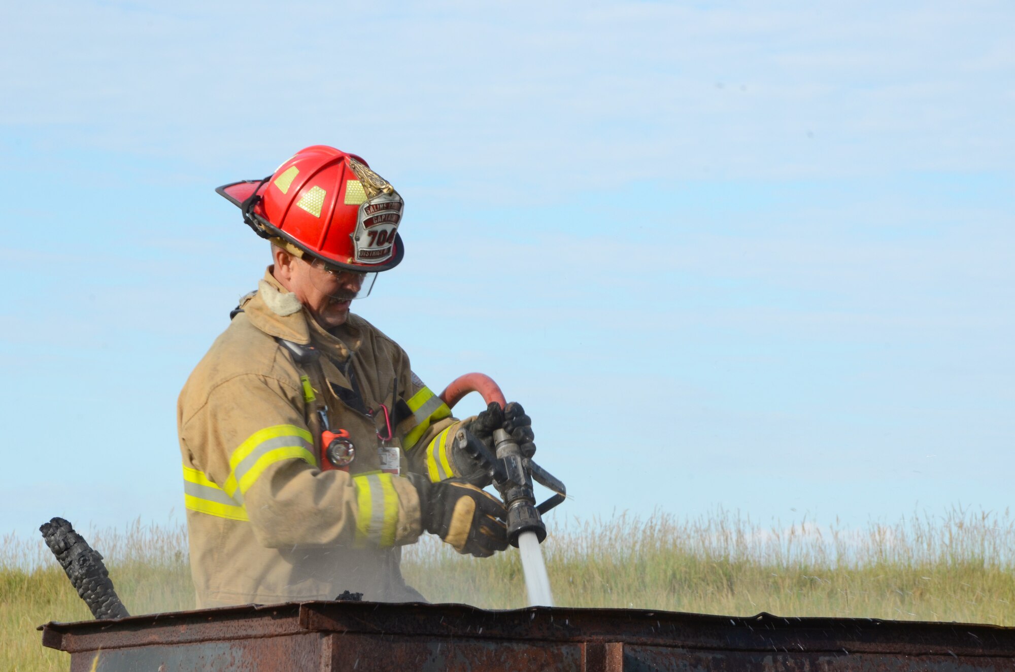 Firefighters from local districts spray burning objects littering the fields where a simulated C-130 “Hercules” crashed at Smoky Hill Weapons Range Sept. 12. Range personnel prepared the crash site with large burn pits which created a high degree of realism during the exercise. (Photo by Senior Airman Lauren Penney, 184th Public Affairs)