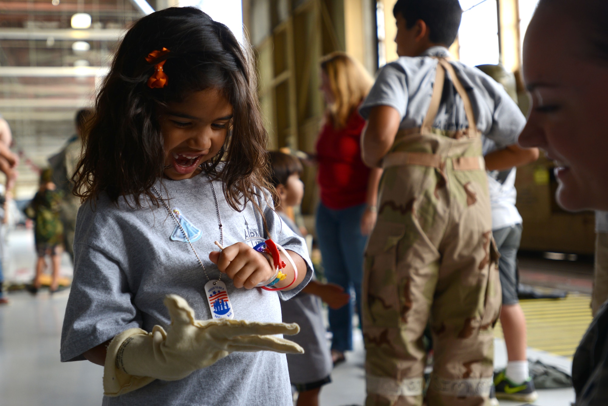 A Team Shaw child wears a glove from a Mission Oriented Protective Posture gear suit during the Kids Meet the Viper event at Shaw Air Force Base, S.C., Sept. 23, 2015. After showing the children how MOPP gear was used, Airmen helped them to try it on for themselves. (U.S. Air Force photo by Airman 1st Class Kelsey Tucker/Released)