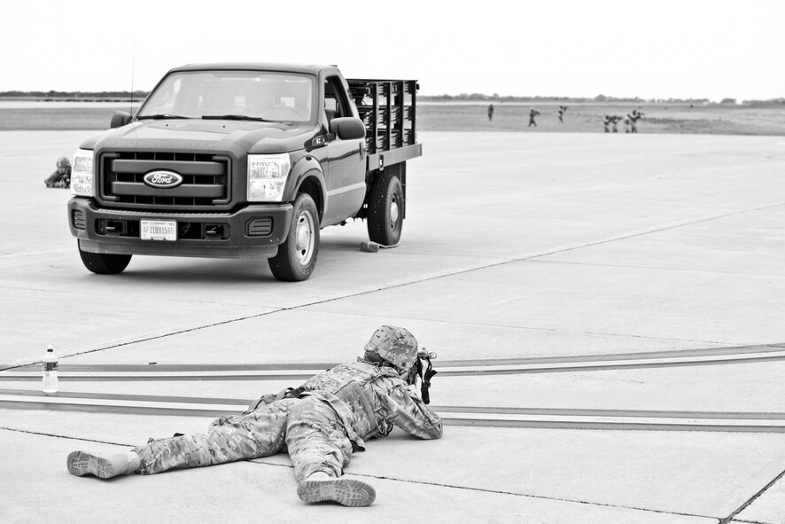 An Airman from the 5th Security Forces Squadron protects a vehicle on the hot cargo pad, while other defenders search the area for oppositional forces while during a training exercise at Minot Air Force Base, N.D., September 24, 2015.  The exercise scenario was a simulated attack by oppositional forces on a convoy carrying valuable materials. (U.S. Air Force photo/Airman 1st Class Justin T. Armstrong)