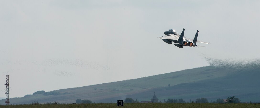 An F-15C Eagle fighter aircraft assigned to the 123rd Expeditionary Fighter Squadron, 142nd Fighter Wing, Oregon Air National Guard, flies over the flightline during a theater security package deployment Sept. 25, 2015, at Campia Turzii, Romania. The U.S. Air Force’s forward presence in Europe allows cooperation among NATO allies and partners to develop and improve ready air forces capable of maintaining regional security. (U.S. Air Force photo by Staff Sgt. Christopher Ruano/Released)