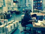 Eugene Harris works at his computer in the packing section at DLA Distribution Jacksonville, Fla., at Gulfport, Miss.