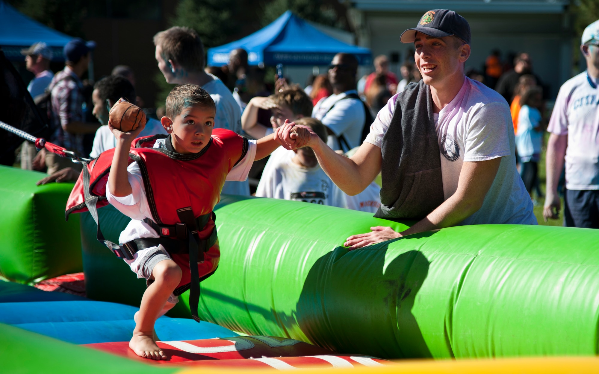 Airman 1st Class Pedro Muina, from the 21st Civil Engineering Squadron fire department, helps Logan Esplin shoot a miniature basketball during Nickelodeon’s Worldwide Day of Play at Patriot Park on Peterson Air Force Base, Colo., Sept. 26, 2015. The annual event encouraged active, healthy lifestyles by providing fun inflatable obstacle courses, games, snacks, a Color Run and demonstrations from the Colorado National Guard, Peterson Fire fighters and Peterson Mobile Emergency Operations Center. (U.S. Air Force photo/Senior Airman Tiffany DeNault)