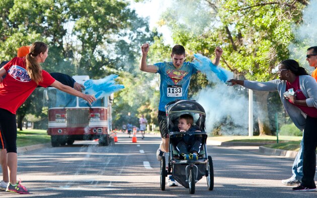 First Lt. Nathan Flack, the 21st Communications Squadron flight commander, and his son, Titus, finish the Color Run during Nickelodeon’s Worldwide Day of Play at Patriot Park on Peterson Air Force Base, Colo., Sept. 26, 2015. The event included a healthy cooking challenge, inflatable obstacle courses, climbing wall, games, snacks and demonstrations from the Peterson Fire Station and Mobile Emergency Operations Center. (U.S. Air Force photo/Senior Airman Tiffany DeNault)