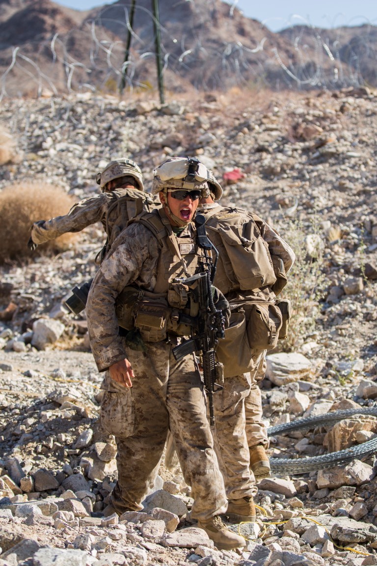 A Marine with Company “F”, 2nd Battalion, 1st Marine Regiment, yells for more Marines to move through the breach during a live fire company assault as part of Realistic Urban Training Exercise (RUTEX) at range 400 aboard Marine Corps Air Ground Combat Center Twenty-nine Palms, Calif., Sept. 5, 2015. RUTEX provides Marines and Sailors of the 13th Marine Expeditionary Unit (13th MEU) an opportunity to perform and practice their duties while deployed in an urban environment. (U.S. Marine Corps photo by Sgt Hector de Jesus/Released)