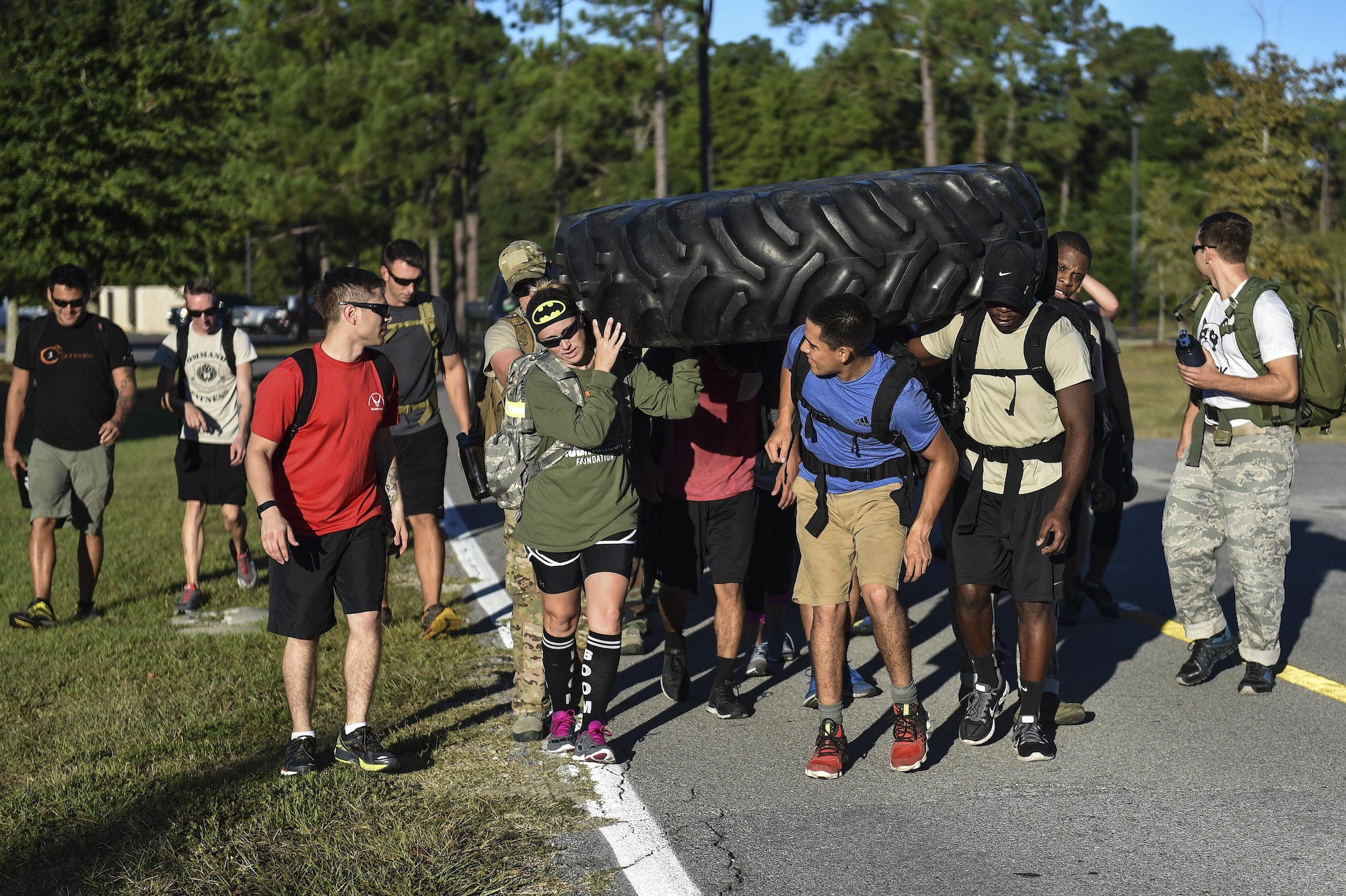 Hurlburt Field Airmen carry a tire from the Aderholt Gym to the fire department during a team cohesion challenge at Hurlburt Field, Fla., Sept. 25, 2015. The challenge brought 28 individuals together for a 7-mile ruck march that included multiple, physically demanding tasks. (U.S. Air Force photo by Senior Airman Jeff Parkinson)