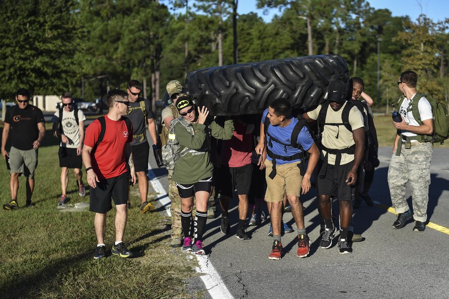 Hurlburt Field Airmen carry a tire from the Aderholt Gym to the fire department during a team cohesion challenge at Hurlburt Field, Fla., Sept. 25, 2015. The challenge brought 28 individuals together for a 7-mile ruck march that included multiple, physically demanding tasks. (U.S. Air Force photo by Senior Airman Jeff Parkinson)