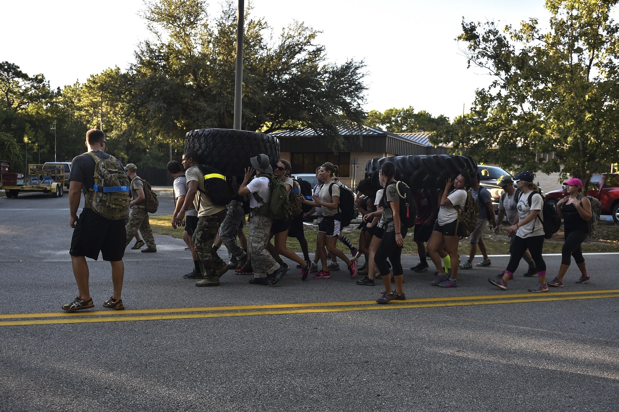 Airmen from Hurlburt Field carry tires from the Aderholt Gym to the fire department during a team cohesion challenge at Hurlburt Field, Fla., Sept. 25, 2015. The challenge brought 28 individuals together for a 7-mile ruck march that included multiple, physically demanding tasks. (U.S. Air Force photo by Senior Airman Jeff Parkinson)