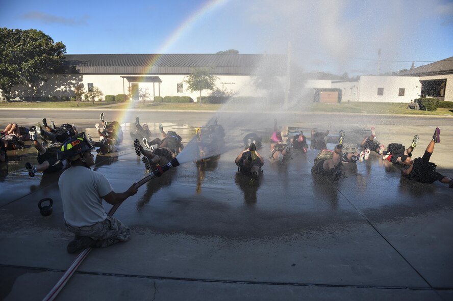 Senior Airman Manuel Rodriguez, 1st Special Operations Civil Engineer Squadron fire fighter, sprays down Airmen participating in the team cohesion challenge at Hurlburt Field, Fla., Sept. 25, 2015. The event challenges a group of Airmen to work together as a team to complete a task. (U.S. Air Force photo by Senior Airman Jeff Parkinson)