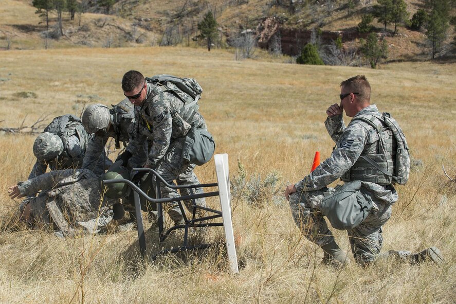 Members of the 307th Security Forces Squadron competition team drag an injured Airman to cover during the Mental and Physical Challenge on Sept. 22, 2015, Camp Guernsey Joint Training Center, Wyo. One member of the six-person team was substituted with a 180-pound dummy, and after dragging it to safety, the remaining team members performed Self-Aid and Buddy Care techniques on a simulated gunshot would to the chest and a leg injury. (U.S. Air Force photo by Master Sgt. Greg Steele/Released)