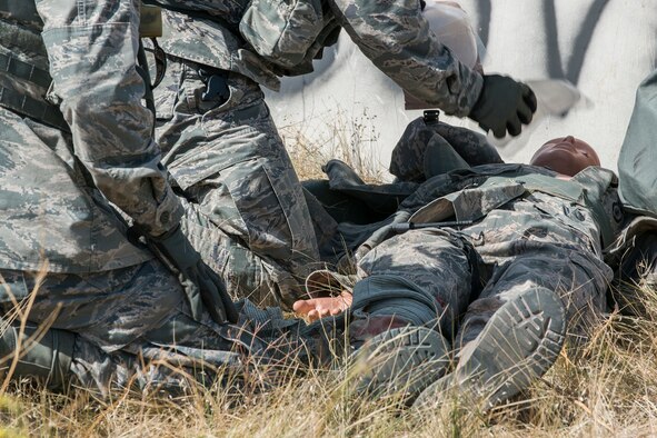 Members of the 307th Security Forces Squadron competition team perform Self-Aid and Buddy Care techniques on a simulated injured Airman during the Mental and Physical (MAP) Challenge on Sept. 22, 2015, Camp Guernsey Joint Training Center, Wyo. The MAP Challenge is a timed event, where Security Forces teams use their land navigation skills to reach check points, testing their team work and ability to complete objectives under harsh and stressful conditions. (U.S. Air Force photo by Master Sgt. Greg Steele/Released)