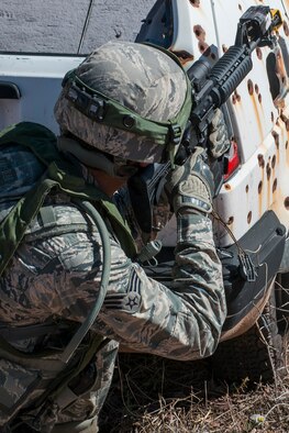 U.S. Air Force Senior Airman Chaz Thomas, 307th Security Forces Squadron, takes cover behind a bullet-riddled vehicle during the Capture and Recovery Challenge on Sept. 24, 2015, Camp Guernsey Joint Training Center, Wyo. The challenge consists of teams eliminating enemy threats and securing a nuclear asset. (U.S. Air Force photo by Master Sgt. Greg Steele/Released)