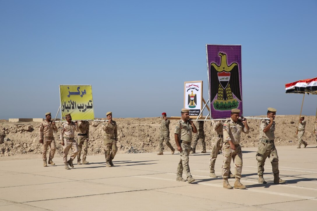Members of the Popular Mobilization Program parade their unit emblems during a graduation ceremony at Al Taqaddum Air Base, Iraq, Sept. 3, 2015. The Popular Mobilization Program is an Iraqi-led, Operation Inherent Resolve program that trains volunteer tribal forces in leadership, small unit tactics and urban warfare to ultimately serve with Iraqi Security Forces in their battle to defeat the Islamic State of Iraq and the Levant and ensure the safety and security of its citizens. (U.S. Marine Corps photo by Cpl. John Baker / released)
