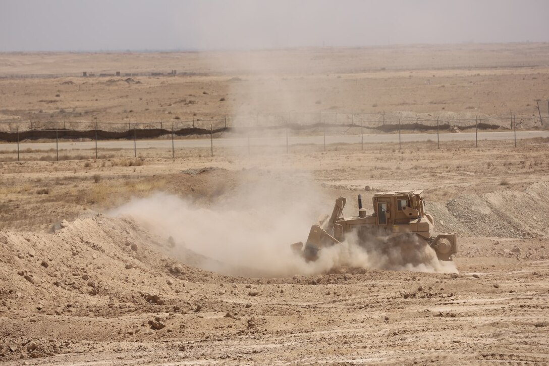 A U.S. Marine builds a defensive berm around the perimeter of Camp Manion, Iraq, Aug. 20, 2015.  Located on Al Taqaddum, Air Base, the camp is named after Marine 1st Lt. Travis Manion, who was killed in action in Anbar province in 2007. Coalition personnel reestablished a presence there in June 2015 to advise and assist the Iraqi security forces. By pairing experienced personnel with their Iraqi counterparts, coalition forces can provide intelligence, logistics and operations planning support to ultimately enable the Iraqi security forces to defeat the Islamic State of Iraq and the Levant. (U.S. Marine Corps photo by Cpl. John Baker/released)