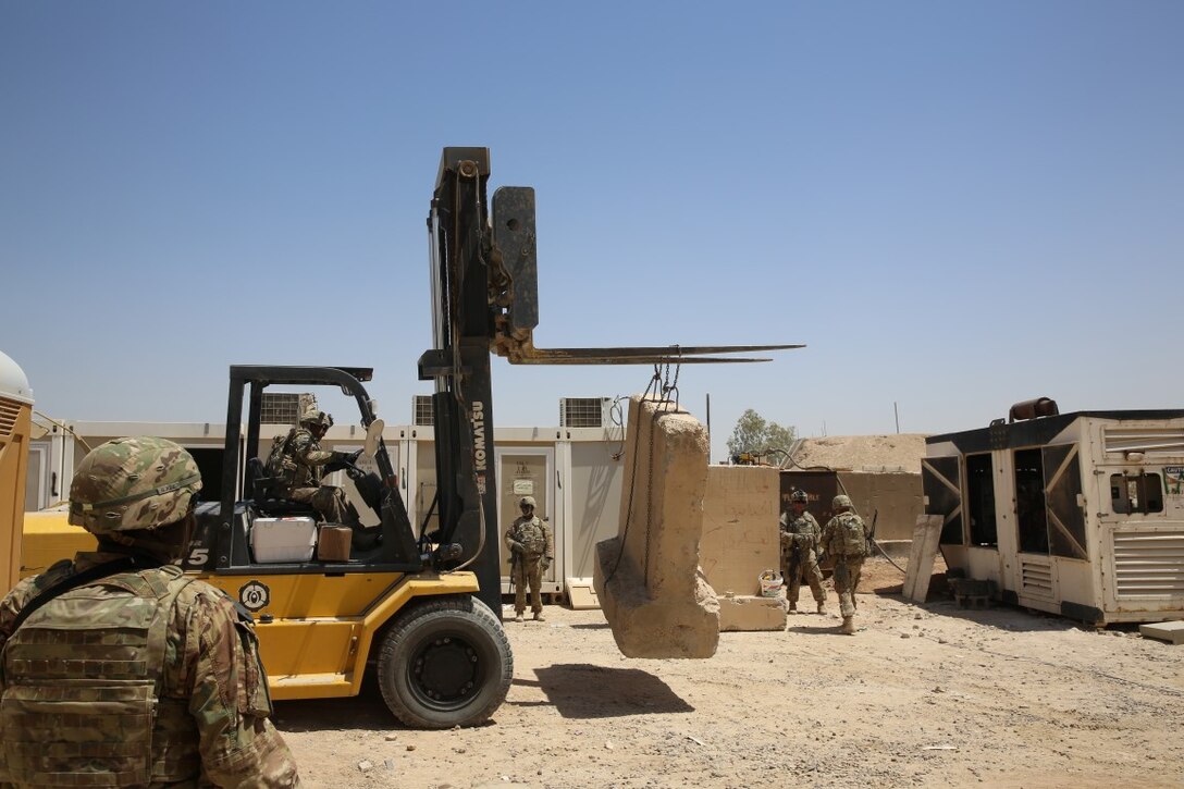 U.S. Soldiers with Task Force Al Taqaddum move concrete barriers to reinforce the living areas at Al Taqaddum Air Base, Iraq, Aug. 19, 2015. The team of soldiers worked quickly and effectively to provide safe structures for the personnel of Task Force Al Taqaddum. Coalition personnel reestablished a presence there in June 2015 to advise and assist the Iraqi security forces. By pairing experienced personnel with their Iraqi counterparts, coalition forces can provide intelligence, logistics and operations planning support to ultimately enable the Iraqi security forces to defeat the Islamic State of Iraq and the Levant. (U.S. Marine Corps photo by Cpl. John Baker/released)