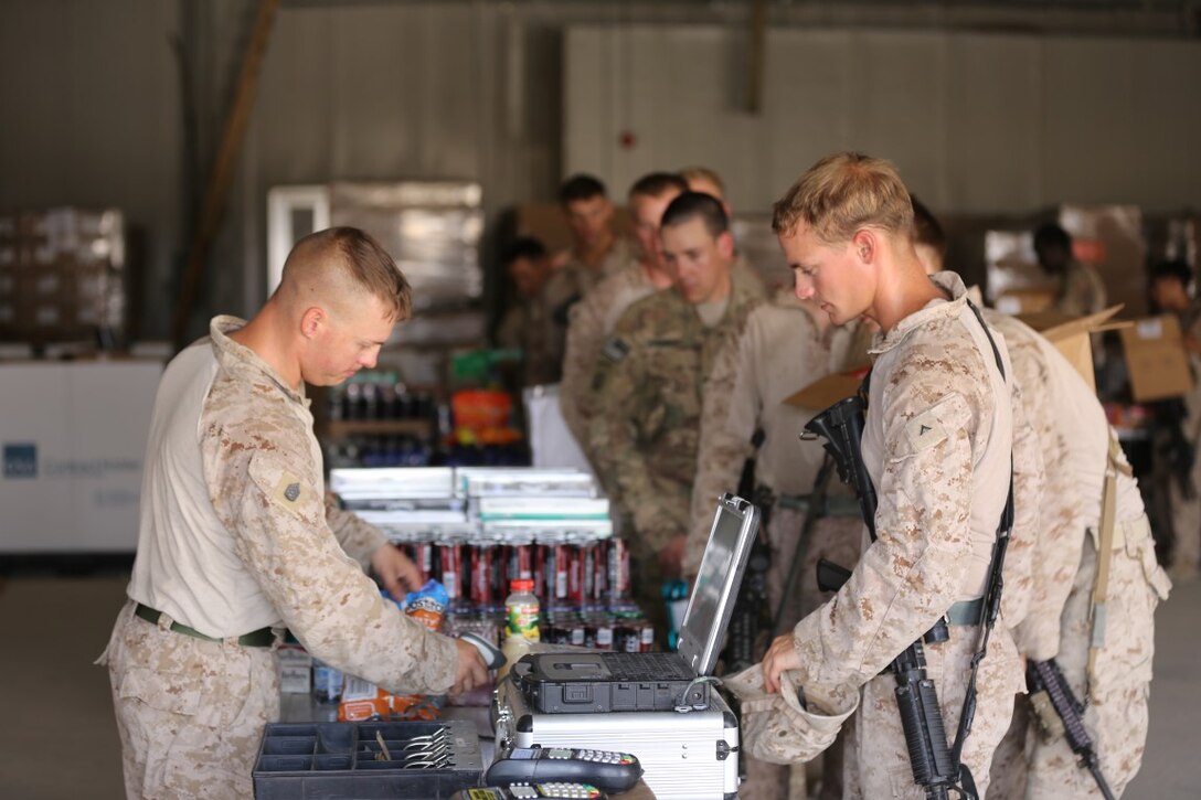 U.S. Marine Lance Cpl. Jarid Ashman, right, a motor transport operator with Task Force Al Taqaddum, makes a purchase from the Warrior Express Team mobile Post Exchange during its visit to Al Taqaddum Air Base, Iraq, Aug. 19, 2015. Coalition personnel reestablished a presence there in June 2015 to advise and assist the Iraqi security forces. By pairing experienced personnel with their Iraqi counterparts, coalition forces can provide intelligence, logistics and operations planning support to ultimately enable the Iraqi security forces to defeat the Islamic State of Iraq and the Levant. (U.S. Marine Corps photo by Cpl. John Baker/released)