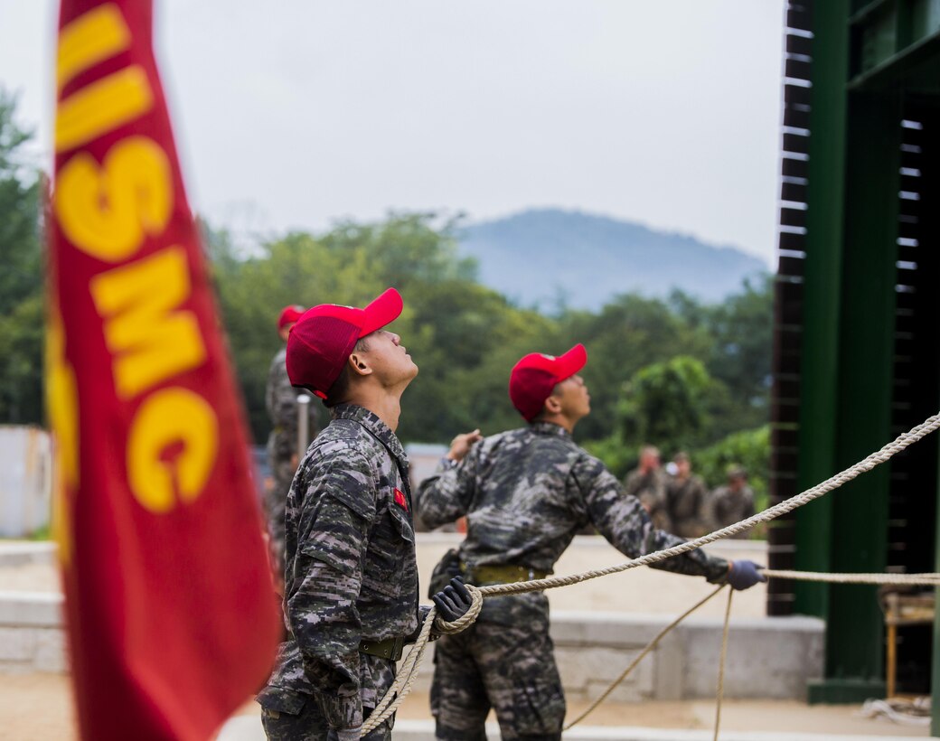 Republic of Korea Marine ranger instructors act as belay men during a company competition among integrated teams of ROK and U.S. Marines during Korean Marine Exchange Program at Yooghuk Dae, Munseu San Mountain, Republic of Korea, Sept. 11, 2015. The U.S. and ROK Marines competed for the fastest company in rappelling, rocking climbing and rope climbing before a sprint to the finish line. KMEP 15-12 is a bilateral training exercise that enhances the ROK and U.S. alliance, promotes stability on the Korean Peninsula and strengthens ROK and U.S. military capabilities and interoperability. The ROK Marines are with 11th Battalion, 1st Regiment, 2nd Marine Division, ROK Headquarters Marine Corps.
