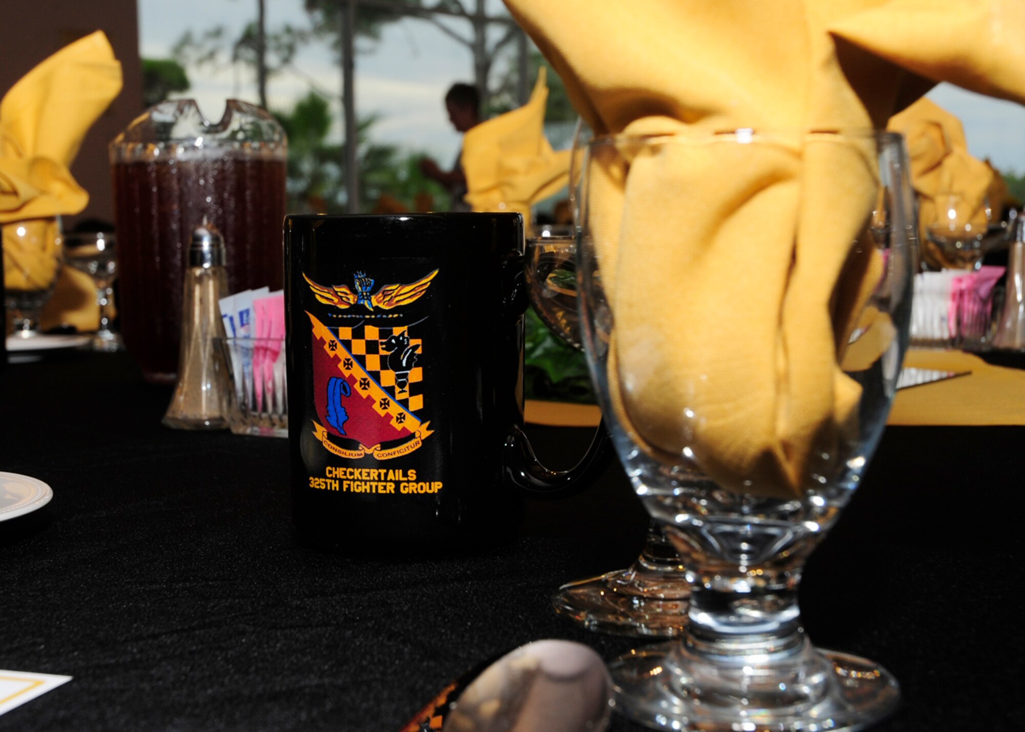 Commemorative mugs sit at the ready Sept. 26 for those in attendance of the 325th Fighter Group Checkertail Reunion.  The Airmen of the 325th FG fought to defeat Axis Powers during World War II across North Africa, Italy, France, Germany and Eastern Europe. The 325th FG destroyed 537 enemy aircraft in aerial combat, 350 enemy aircraft on the ground, were awarded two Distinguished Unit citations and had 27 aces recognized during two years of combat. Their motto, "Locare et Liquidare", meaning Locate and Liquidate, brilliantly described the Checkertails' mission, focus and correspondingly exceptional results. (U.S. Air Force photo by Airman 1st Class Solomon Cook/ Released)