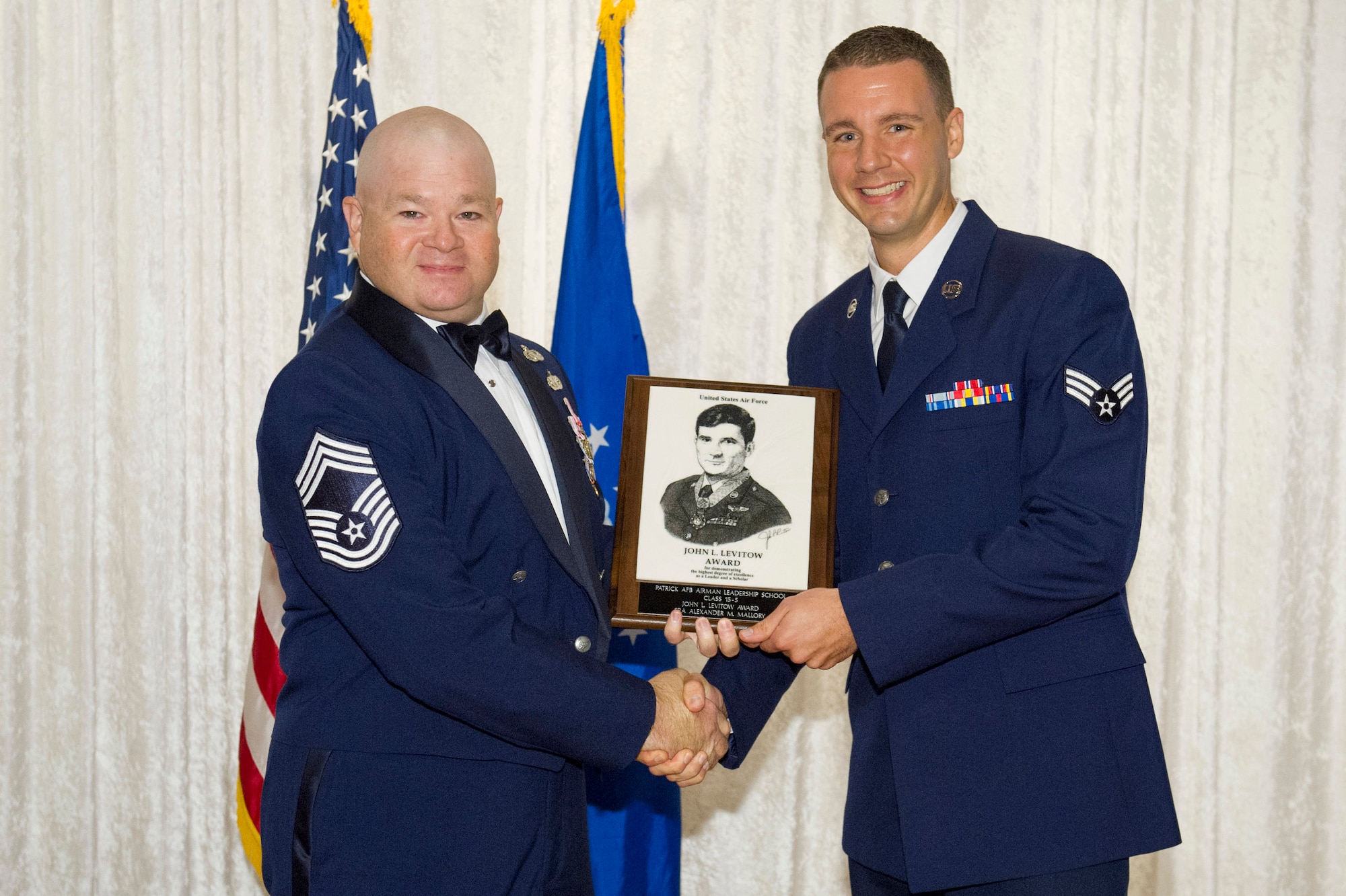 Chief Master Sgt. James Isom III, 45th Operations Group chief, presents Senior Airman Alexander Mallory, assigned to the Air Force Technical Applications Center, with the John L. Levitow Award, Sept. 29, 2015, at Patrick Air Force Base, Fla., Tides Club, during an ALS graduation ceremony. The John L. Levitow Award is the highest award for enlisted Professional Military Education in the Air Force and is presented to the student who demonstrates the most outstanding leadership and scholastic achievement throughout ALS. (U.S. Air Force photo/Matthew Jurgens/Released)