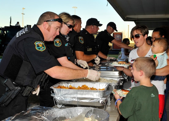 Police offers from the Glendale Police Department serve food during the Deployed Family Day September 25, 2015, at Fowler Park on Luke Air Force Base, Arizona. The Glendale P.D.  sponsored the event and wanted to support and to give back to the families of the Luke community who are remotely separated or separated by deployments. (U.S. Air Force photo by Staff Sgt. Marcy Copeland)