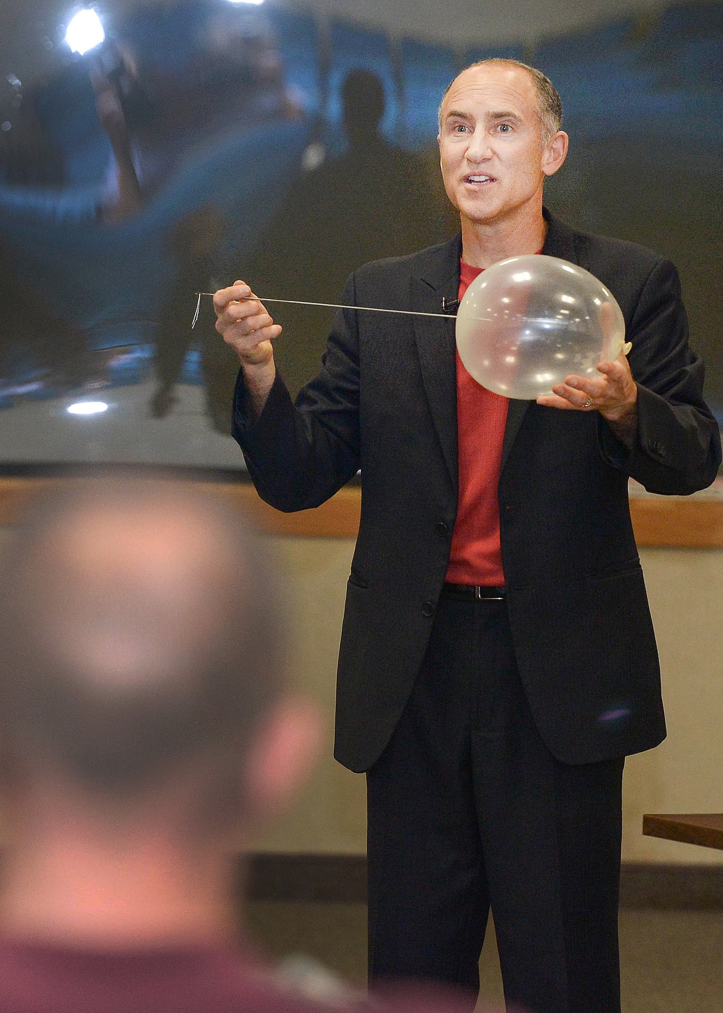 Brad Barton, a continuous improvement leadership expert, magician and motivational speaker, places a large metal pin through a balloon during a presentation at the Hanscom Conference Center Sept. 29. Through the use of magic, Barton highlighted the building of personal and family resiliency during his presentation. (U.S. Air Force photo by Jerry Saslav)