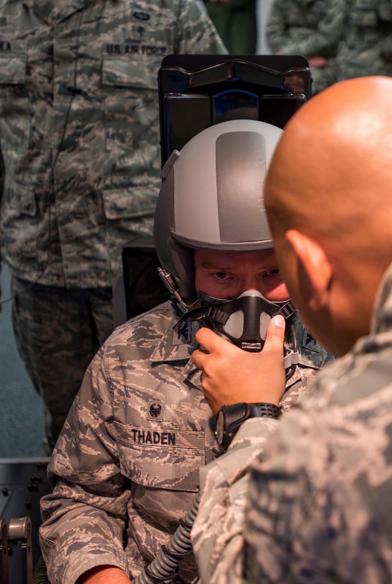 Staff Sgt. Nazareth Oliver, 87th Aerospace Medicine Squadron physiologist, helps Col. Frederick D. Thaden, Joint Base McGuire-Dix-Lakehurst and 87th Air Base Wing commander, don a flight helmet and mask before demonstrating a hypoxia training system during its unveiling at JB MDL, N.J., Sept. 21, 2015. The altitude chamber previously used has a vacuum that removes the pressure to mimic pressure in flight at 25,000 feet, where the new one-person simulator uses a mixture of nitrogen and air brought in by gas cylinders through the reduced oxygen breathing device. (U.S. Air Force photo by Senior Airman Tara A. Williamson/Released)