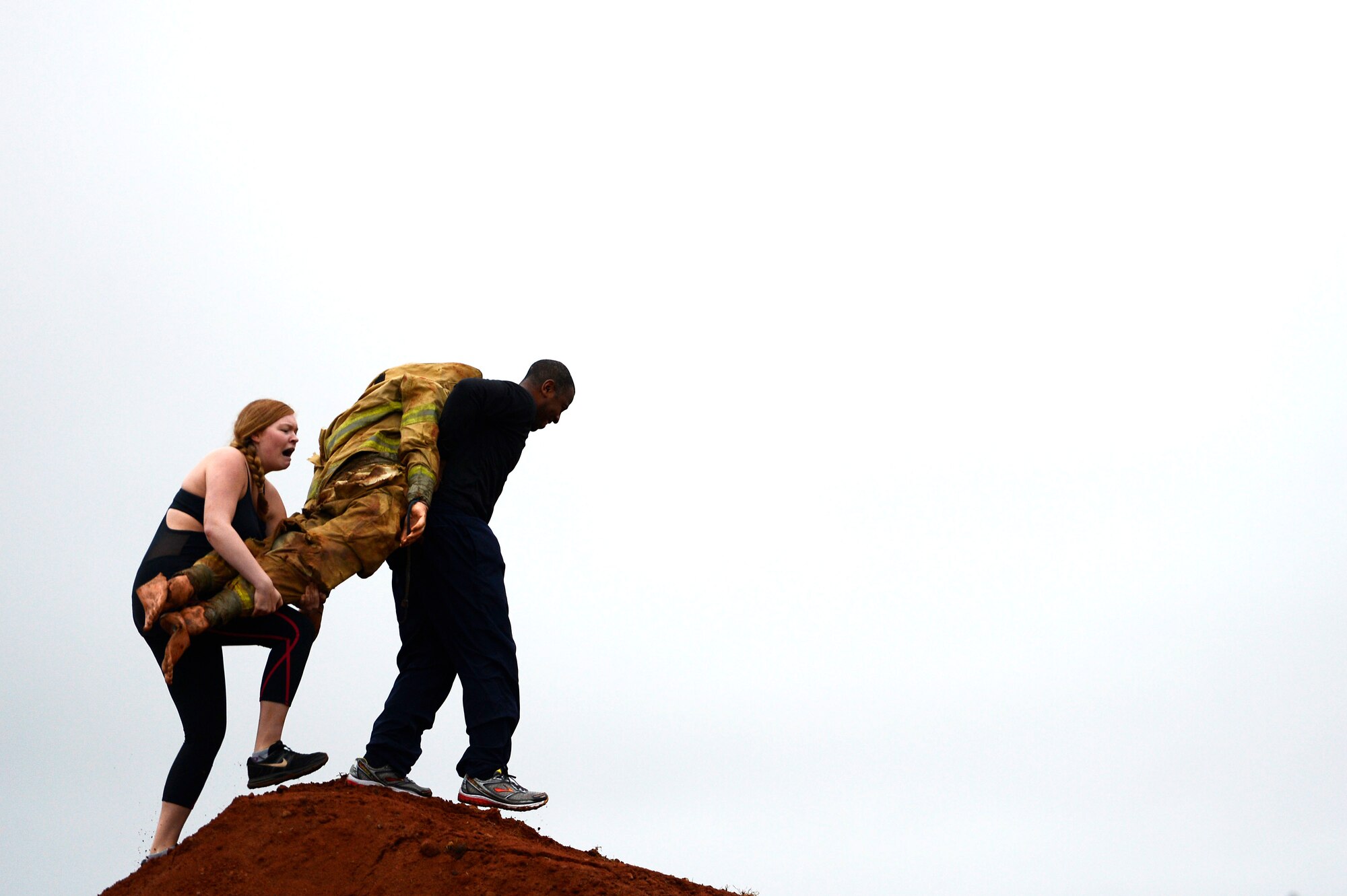 U.S. Air Force Airmen carry a weighted dummy during a 20th Fighter Wing Comprehensive Airman Fitness week obstacle course at Shaw Air Force Base, S.C., Sept. 25, 2015.  During the first of eight obstacles, Airmen carried the dummy over a large dirt hill. (U.S. Air Force photo by Senior Airman Jensen Stidham/Released)