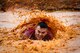 U.S. Air Force Senior Airman Jonathan Bass, 20th Fighter Wing Public Affairs photojournalist, lands in a mud pit during a 20th Fighter Wing Comprehensive Airman Fitness week obstacle course at Shaw Air Force Base, S.C., Sept. 25, 2015. Airmen participated in varying obstacles throughout the run to test their endurance and resiliency to changing conditions. (U.S. Air Force photo by Senior Airman Jensen Stidham/Released)