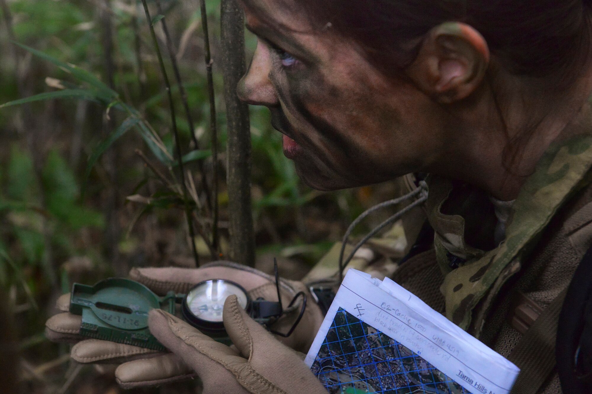Capt. Allison Ohlinger, 36th Airlift Squadron instructor navigator, uses a compass to navigate for her team during a Survival, Evasion, Resistance and Escape combat survival course at Tama Hills Recreation Area, Japan, Sept. 24, 2015. SERE uses realistic wilderness situations to teach students the importance, difficulty and technique of navigation using simple instruments. (U.S. Air Force photo by Airman 1st Class Elizabeth Baker/Released)