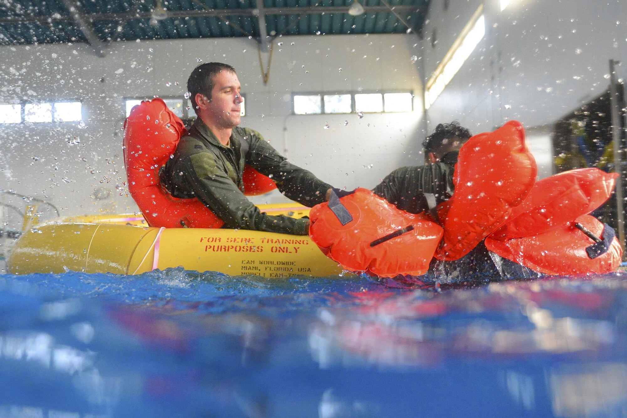 Capt. Michael Farrara, 459th Airlift Squadron C-12 pilot, pulls Tech. Sgt. Kyle Favorite, 36th Airlift Squadron evaluator loadmaster, into a life raft during the Survival, Evasion, Resistance and Escape water survival course at Yokota Air Base, Japan, Sept. 22, 2015. The water survival course familiarizes students with the equipment and procedures used in an aircraft emergency. (U.S. Air Force photo by Airman 1st Class Elizabeth Baker/Released)