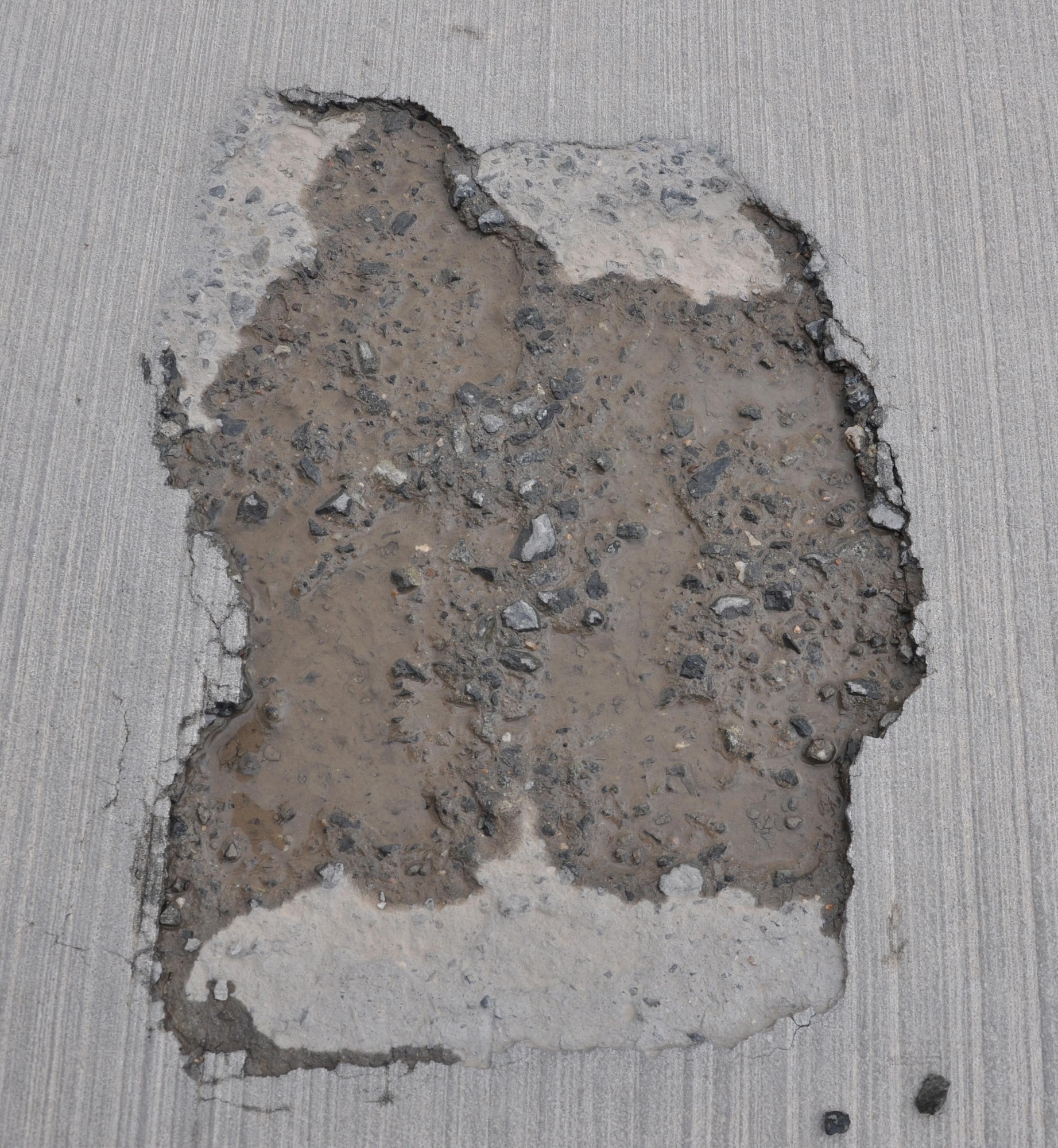 A large hole on an aircraft parking ramp containing several rocks is found at Al Udeid Air Base, Qatar March 17. Members of the 379th Expeditionary Operations Support Squadron’s Airfield Management team conduct checks of more than 49 million square feet of pavement at AUAB every day. The team reports any discrepancies that could interfere with flying operations, such as the hole pictured here. In 2015, the team supported more than 20,000 sorties. (U.S. Air Force photo by Tech. Sgt. James Hodgman/Released)