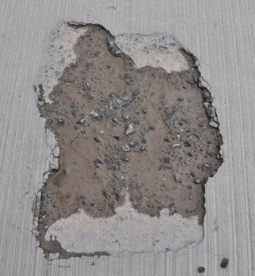 A large hole on an aircraft parking ramp containing several rocks is found at Al Udeid Air Base, Qatar March 17. Members of the 379th Expeditionary Operations Support Squadron’s Airfield Management team conduct checks of more than 49 million square feet of pavement at AUAB every day. The team reports any discrepancies that could interfere with flying operations, such as the hole pictured here. In 2015, the team supported more than 20,000 sorties. (U.S. Air Force photo by Tech. Sgt. James Hodgman/Released)