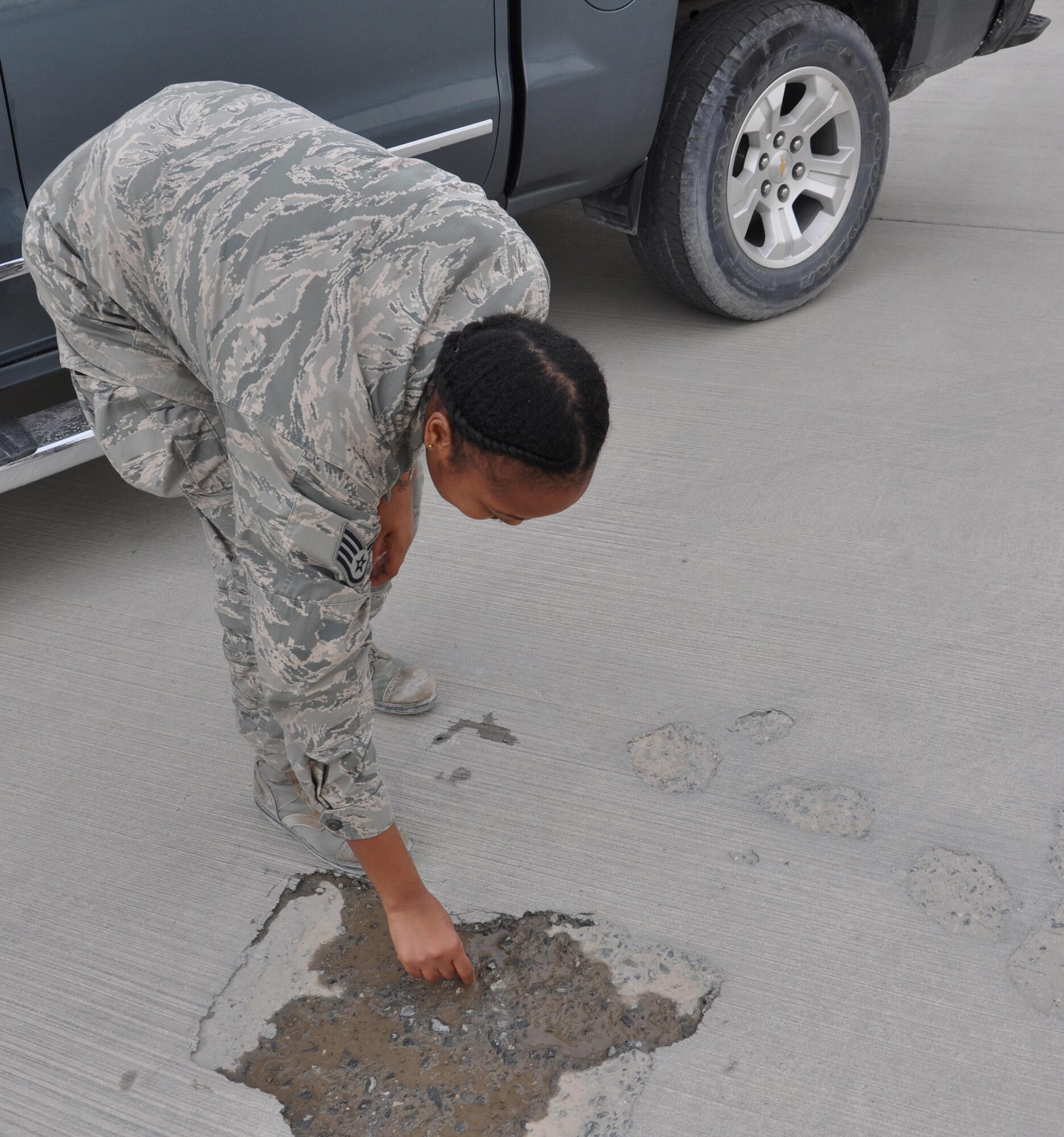 Staff Sgt. Talia Fulgham, 379th Expeditionary Operations Support Squadron Airfield Management operations noncommissioned officer in charge from Alliance, Ohio, removes rocks from an aircraft parking ramp at Al Udeid Air Base, Qatar March 17. As the NCOIC of the 379 EOSS Airfield Management office, Fulgham is responsible for ensuring all foreign objects and debris are removed from the airfield.  She and her Airmen conduct several FOD checks every day to prevent aircraft damage. The Airfield Management team supported more than 20,000 sorties in 2015. (U.S. Air Force photo by Tech. Sgt. James Hodgman/Released)