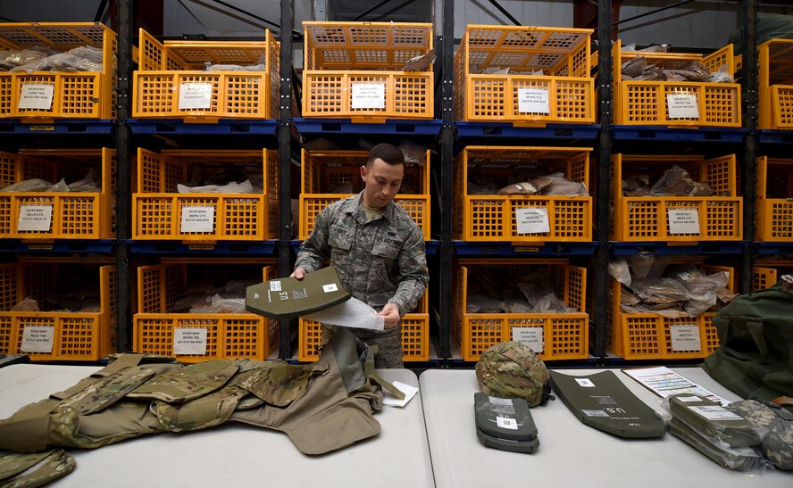 Senior Airman John Flores, an Expeditionary Theater Distribution Center technician assigned to the 386th Expeditionary Logistics Readiness Squadron, assembles an improvised outer tactical vest at an undisclosed location in Southwest Asia, March 15, 2016. The material management flight manages all base supplies and equipment with more than half a million assets. (U.S. Air Force photo by Staff Sgt. Jerilyn Quintanilla)