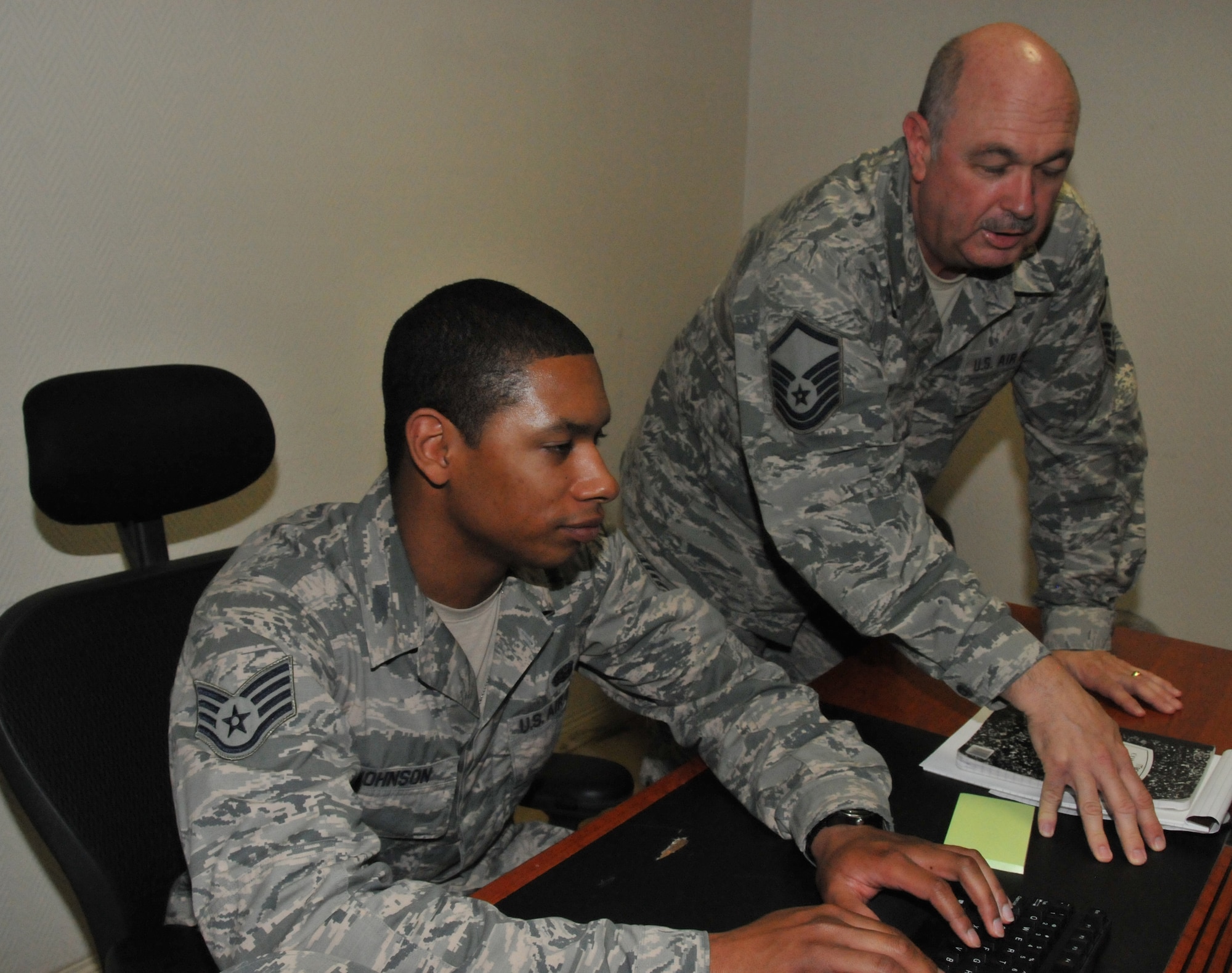 Staff Sgt. Aaron Johnson (left) and Master Sgt. Kenneth Law (right), 379th Expeditionary Communications Squadron Cyber Surety specialists, discuss an email sent from the Network Operations and Security Center March 18 at Al Udeid Air Base, Qatar. The Cyber Surety team handles network requests to grant personnel  network access here. (U.S. Air Force photo by Tech. Sgt. Terrica Y. Jones/Released)