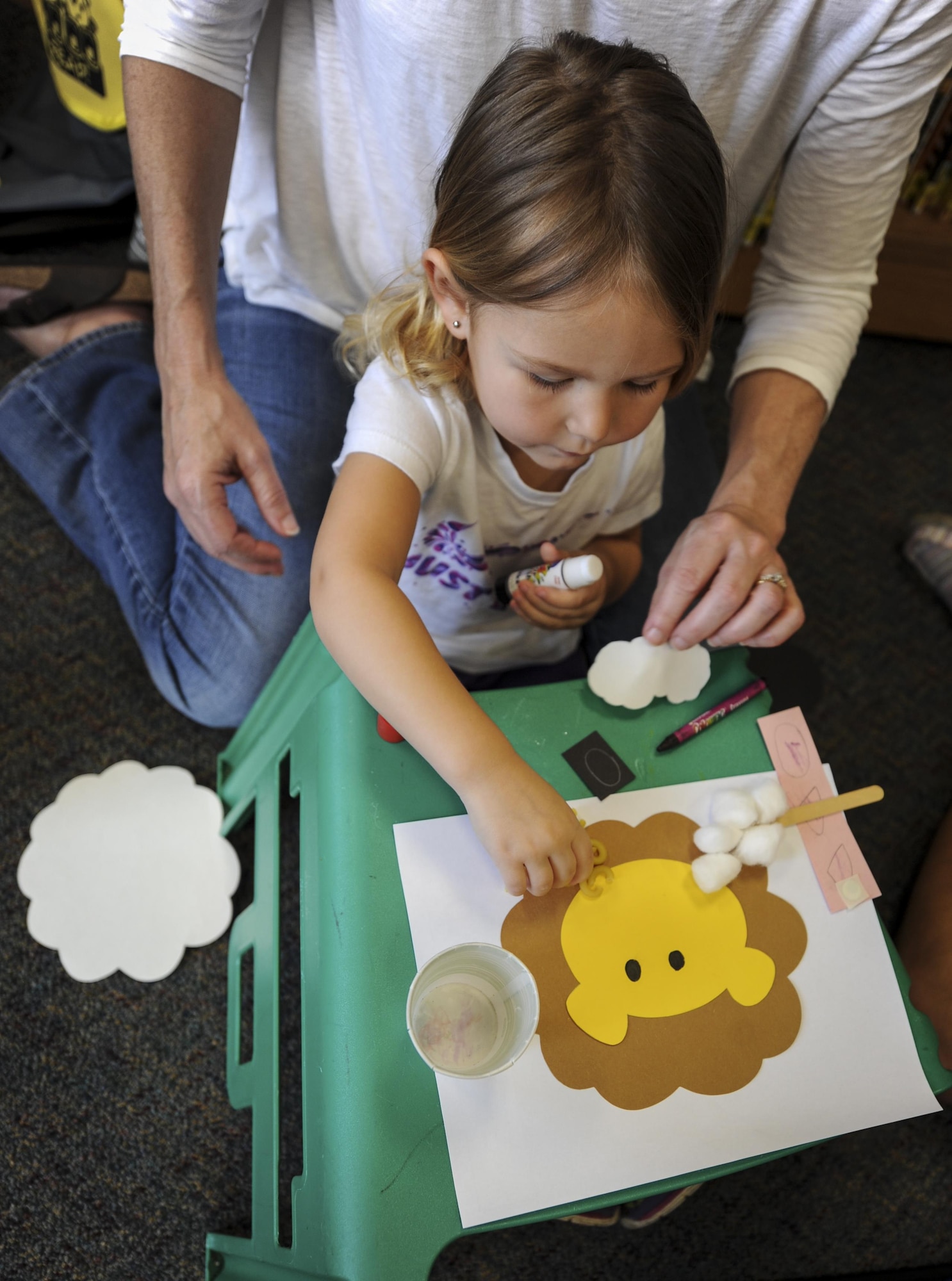 A young girl prepares to glue a piece of macaroni on paper during craft time at the library, Hurlburt Field, Fla., March 31, 2016. Every Thursday, the library hosts a reading time with a guest speaker who reads to children. This event enables parents to network and helps children work on literacy skills, fine motor capabilities and social skills. (U.S. Air Force photo by Senior Airman Meagan Schutter)