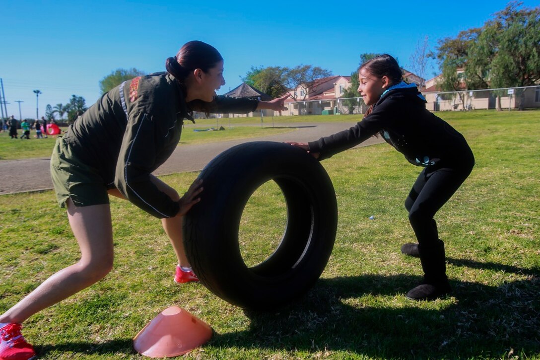 MARINE CORPS BASE CAMP PENDLETON, Calif. – Cpl. Richelle Delapaz, left, guides Kayla Morley through an obstacle course at North Terrace Elementary, March 25, 2016. Approximately 30 Marine volunteers with the Single Marine Program facilitated a series of exercises and competitions including an obstacle course relay race and tug-of-war as part of a Physical Education Fitness Challenge. The challenge encourages children to stay active and helps Marines engage with their local community. Delapaz, a native of Corpus Christi, Texas, is a field radio operator with 9th Communication Battalion, I Marine Expeditionary Force Headquarters Group. Morley is a second grade student at North Terrace Elementary. (U.S. Marine Corps photo by Lance Cpl. Caitlin Bevel/RELEASED)