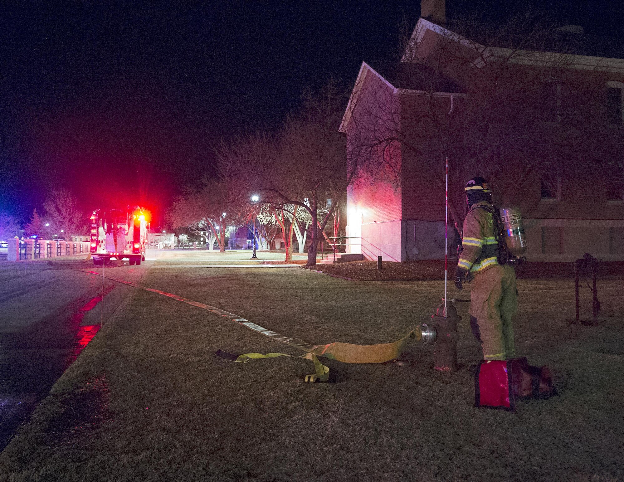 A firefighter with the F.E. Warren Air Force Base, Wyo., Fire Department lay hose from a hydrant to their truck March 9, 2016, as they respond to a fire alarm in the 90th Missile Wing headquarters building. (U.S. Air Force photo by R.J. Oriez)