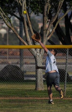A player from the 57th Maintenance Squadron Munitions Flight intramural softball team attempts to catch a fly ball on the run during a practice game at Nellis Air Force Base, Nev., March 28, 2016. Softball games, which are held Monday through Thursday from 5:30 to 7:30 p.m., are meant to build goodwill between the units. (U.S. Air Force photo by Airman 1st Class Kevin Tanenbaum)