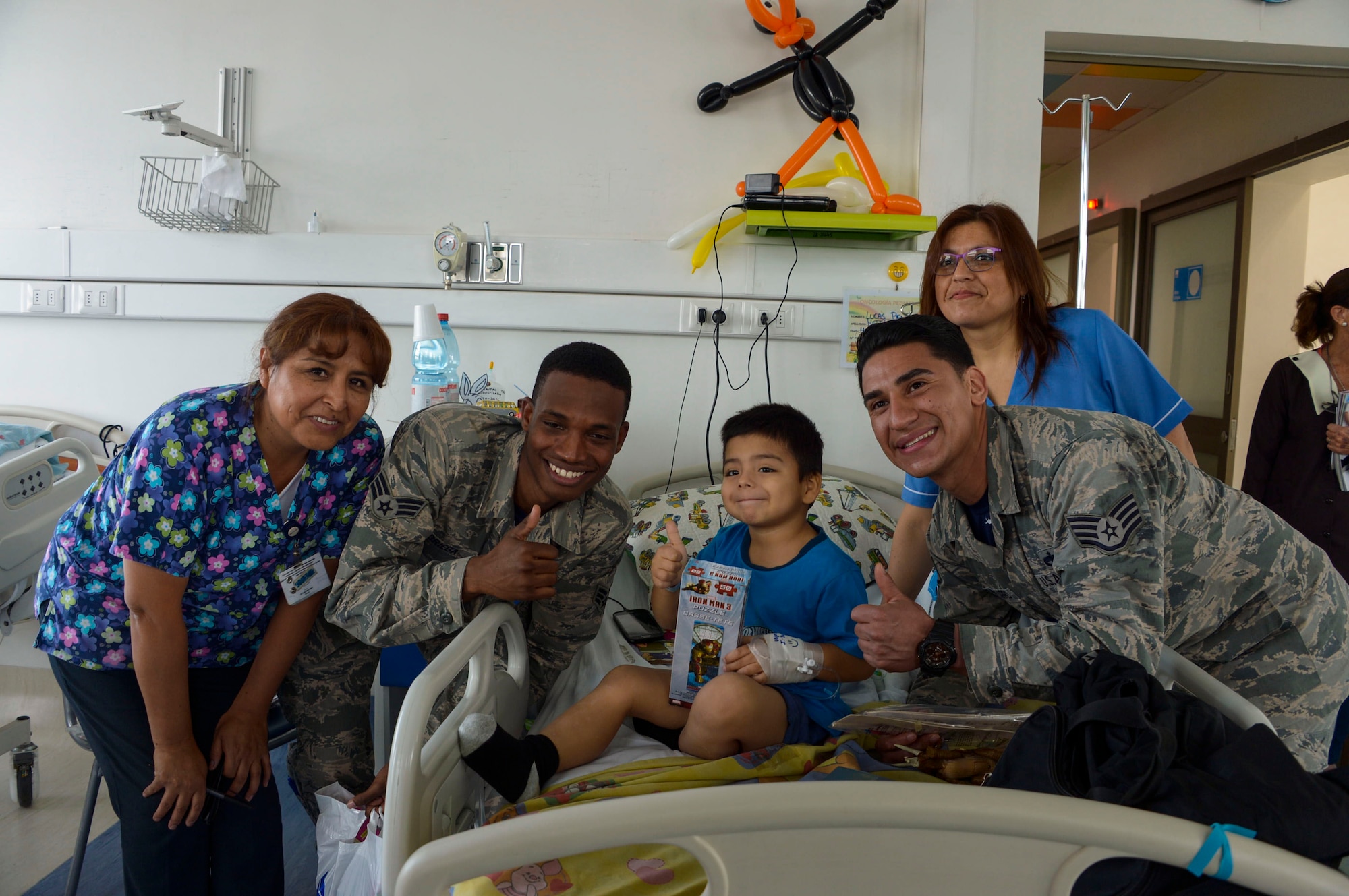 Senior Airman Tyrell Noriega and Staff Sgt. Juan Gomez-Navarro, F-22 Demonstration Team members, pose with a child at San Juan de Dios hospital in Santiago, Chile, March 31, 2016.  The Airmen are in Chile to participate in the 2016 FIDAE Air and Space Trade Show and spent some of their down-time visiting children in multiple hospitals.  (U.S. Air Force photo by Tech. Sgt. Heather Redman/Released)