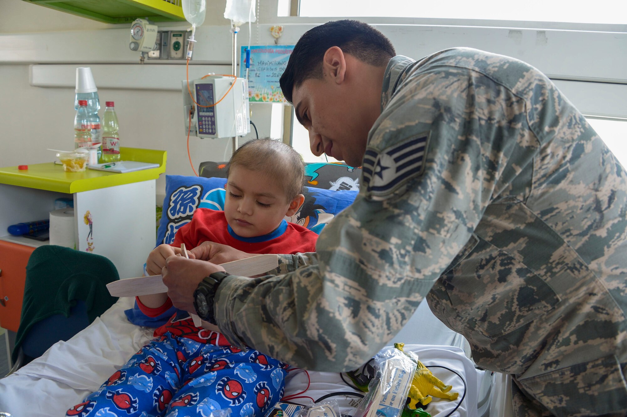 Staff Sgt. Juan Gomez-Navarro, fuel systems specialist with the F-22 Demonstration Team, helps a child build a plane at San Juan de Dios hospital in Santiago, Chile, March 31, 2016.  The Airmen are in Chile to participate in the 2016 FIDAE Air and Space Trade Show and spent some of their down-time visiting children in multiple hospitals.  (U.S. Air Force photo by Tech. Sgt. Heather Redman/Released)