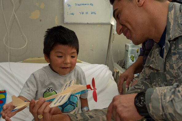 Staff Sgt. Juan Gomez-Navarro, fuel systems specialist with the F-22 Demonstration Team, helps a child build a plane at San Juan de Dios hospital in Santiago, Chile, March 31, 2016.  The Airmen are in Chile to participate in the 2016 FIDAE Air and Space Trade Show and spent some of their down-time visiting children in multiple hospitals.  (U.S. Air Force photo by Tech. Sgt. Heather Redman/Released)