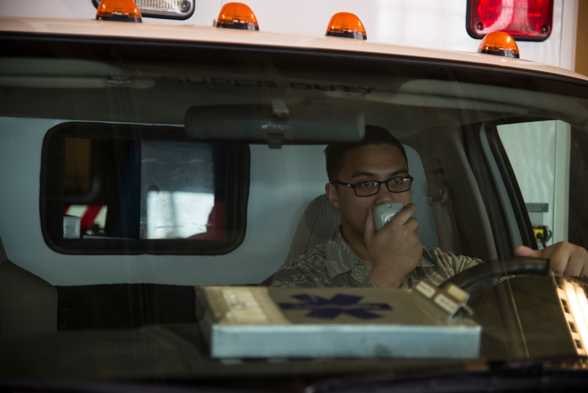 Senior Airman Lenard Catalan, 5th Medical Group emergency medical technician, talks over an ambulance radio during a simulated response at Minot Air Force Base, N.D., March 18, 2016. Catalan and other civilian paramedics in his section work 24 to 72 hour shifts supporting the medical needs of base Airmen and their families.  (U.S. Air Force photo/Airman 1st Class Christian Sullivan)