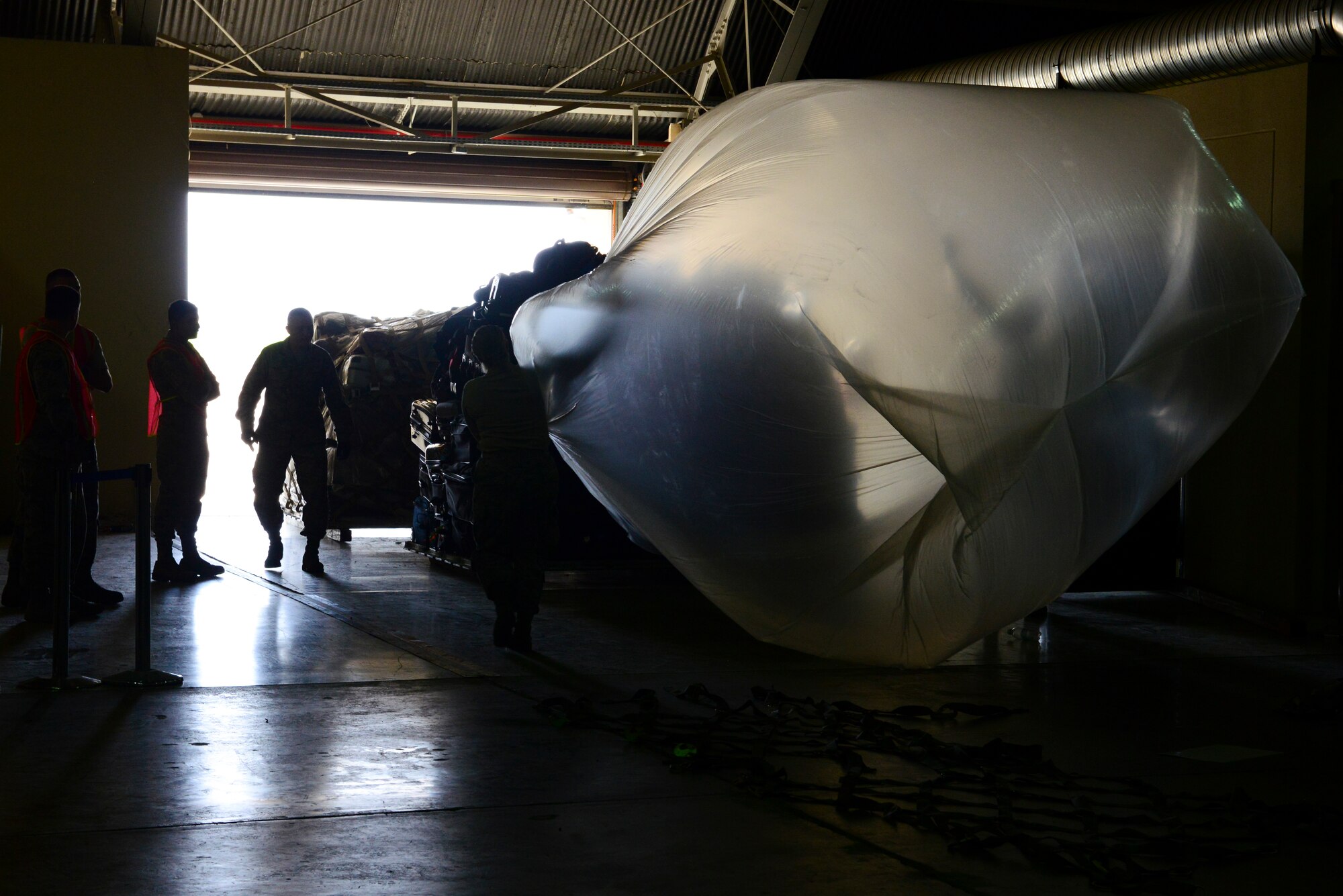 Members of the 728th Air Mobility Squadron along with volunteers, cover a pallet of luggage, March 31, 2016, at Incirlik Air Base, Turkey. Pallets of luggage were built for Families of U.S. Airmen and Department of Defense civilians departing Incirlik during an ordered departure. (U.S. Air Force photo by Staff Sgt. Caleb Pierce/Released)