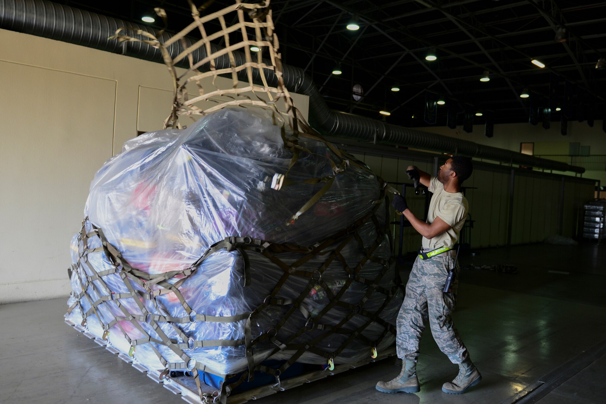 U.S. Air Force Airman Ennis Roberson, 728th Air Mobility Squadron aircraft service apprentice, throws a tie-down net over a pallet of luggage, March 31, 2016, at Incirlik Air Base, Turkey. Pallets were built and staged to load in aircraft for Department of Defense dependents assigned to Incirlik AB. (U.S. Air Force photo by Staff Sgt. Caleb Pierce/Released)